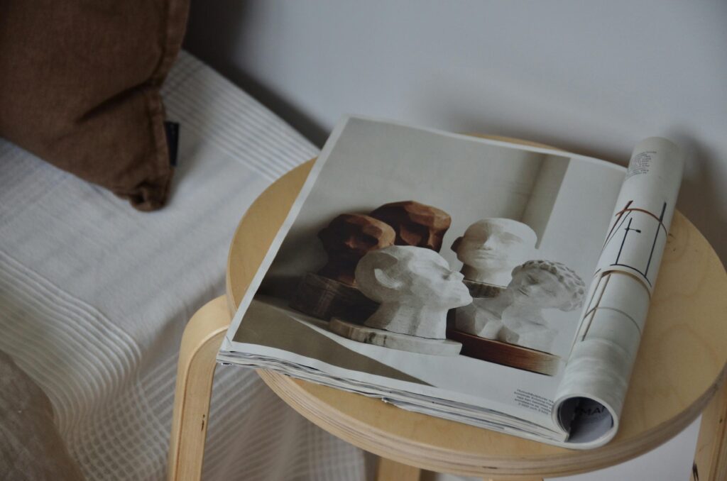 A stylish magazine with art sculptures on a wooden stool, perfect for decor inspiration.